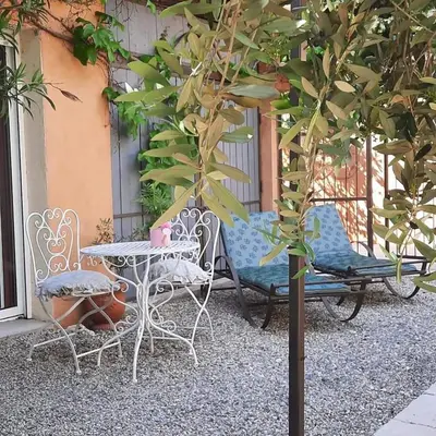 a table and chairs and a table and a tree at Gite Au fond du jardin in Saint-Saturnin-lès-Avignon