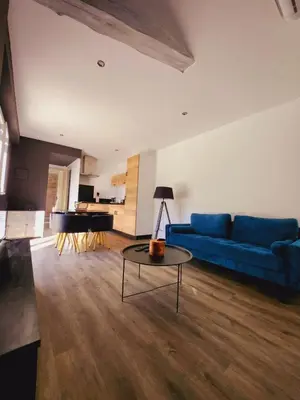 a living room with a blue couch and a table at Bienvenue à L'ÉCRIN avec piscine privée in LʼIsle-sur-la-Sorgue