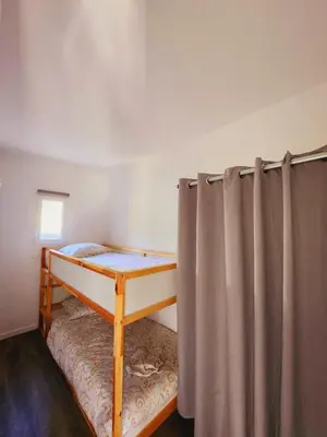 a bedroom with a bunk bed and a curtain at Bienvenue à L'ÉCRIN avec piscine privée in LʼIsle-sur-la-Sorgue