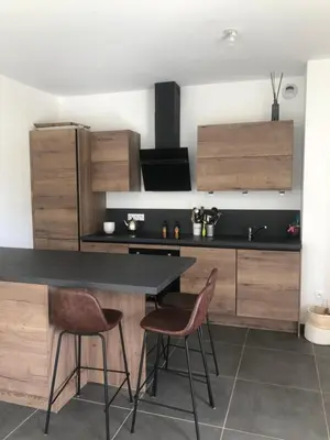 a kitchen with a black counter and wooden cabinets at Appartement Aix en Provence vue Ste Victoire - BATIMENT B11 - 13090 AIX EN PROVENCE in Aix-en-Provence