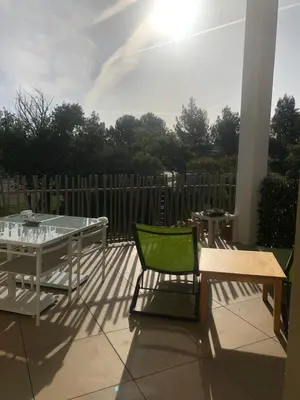 a patio with a table and a green chair at Appartement Aix en Provence vue Ste Victoire - BATIMENT B11 - 13090 AIX EN PROVENCE in Aix-en-Provence