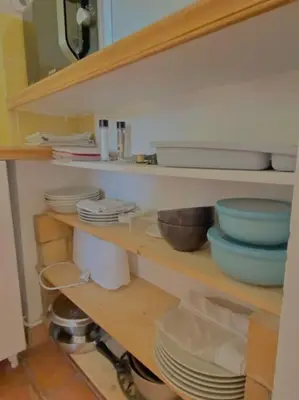 a kitchen shelf with plates and bowls on it at Maisonnette à la campagne. Idéal Télétravail in Éguilles
