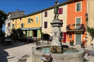 a fountain in the middle of a courtyard with buildings at Hôtel Restaurant L’Observatoire in Saint-Michel-lʼObservatoire