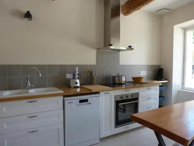 a kitchen with white cabinets and a wooden table at Gite du domaine Saint-Marc, entre Ventoux et dentelles de Montmirail in Caromb