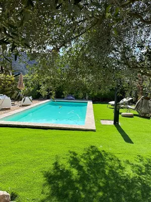 a swimming pool in the middle of a green lawn at La Maiz in Maubec