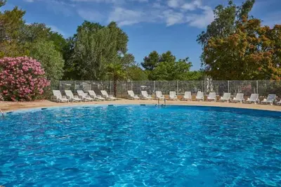 a large swimming pool with chairs and trees at MOBIL HOME LMNP GUIGON in La Roque-dʼAnthéron