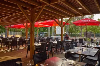 a restaurant with tables and chairs and red umbrellas at MOBIL HOME LMNP GUIGON in La Roque-dʼAnthéron