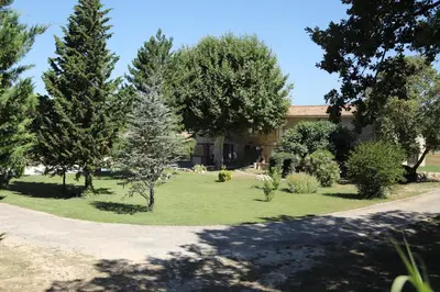 a garden with trees and a house in the background at La Bastide au coeur de la Provence in Pertuis
