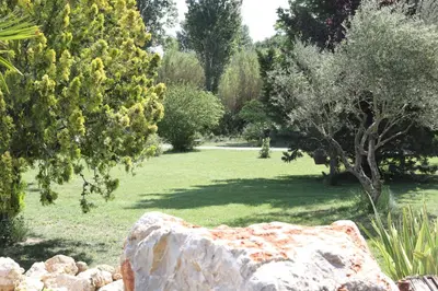 a garden with a rock and trees and grass at La Bastide au coeur de la Provence in Pertuis