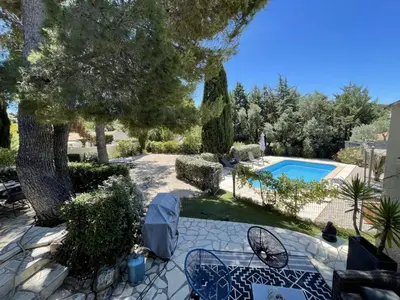 a garden with a pool and trees and chairs at Villa avec Piscine au coeur de la campagne provençale in Lançon-Provence