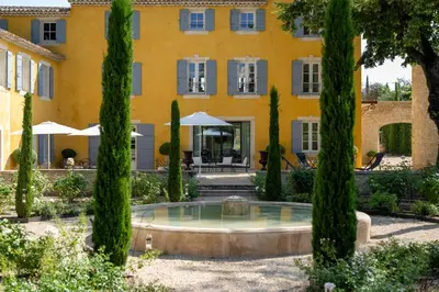 a sunset over a swimming pool with a chair and umbrella at Le Domaine du Fortin in Ménerbes