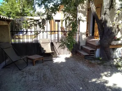 a patio with a chair and a bench and a tree at Le mas de la joëlette in Vedène
