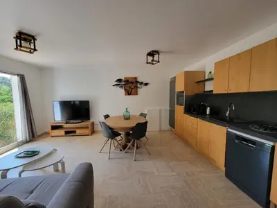 a living room with a table and a kitchen at Gîte élégant au calme in Mazan