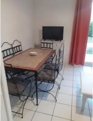 a dining room with a table and chairs and a television at Belle Maisonette dans Residence 3* avec piscine partagée in Saint-Saturnin-lès-Avignon