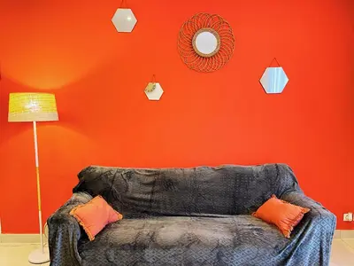 a couch in a room with an orange wall at Carré Rouge*Gare Sncf*Fibre Wifi in Miramas