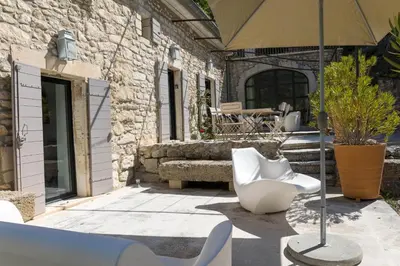 a patio with two white chairs and an umbrella at Superbe Mas Authentique du Luberon Courroussouvo in Oppède