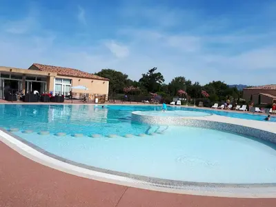 a large swimming pool with blue water in front of a building at Maison conviviale à Aubignan avec piscine partagée in Aubignan