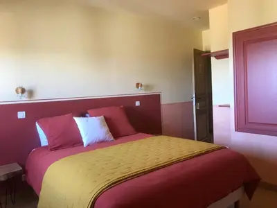 a bedroom with a large bed with pink and yellow sheets at L’OBSERVATOIRE in Saint-Michel-lʼObservatoire