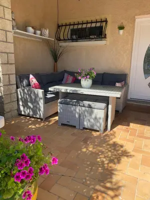 a patio with a couch and a table and flowers at Villa des palmiers in Saint-Saturnin-lès-Avignon