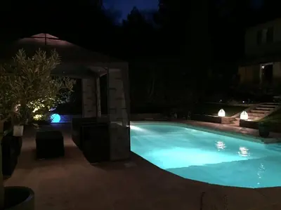 a large swimming pool at night with lights at Gîte de charme La Manola in Rognes