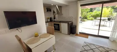 a kitchen with a table and a tv on a wall at MyLuberon-Appartement au pied du Luberon in Lauris