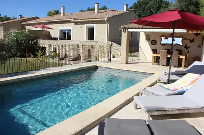 a swimming pool with chairs and an umbrella and a house at Escapade en Provence, Gîte à Lagnes, Luberon, Vaucluse in Lagnes