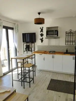 a kitchen with white cabinets and a table with stools at Studio de charme en Provence in Caromb