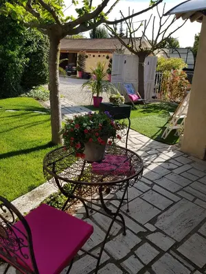 a patio with chairs and a table with a pot of flowers at A l'Orée du Pin in Puyricard