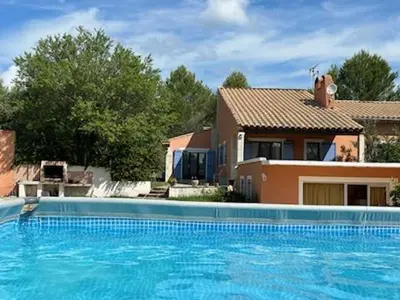 a large blue swimming pool in front of a house at Location saisonnière villa Lauris in Lauris
