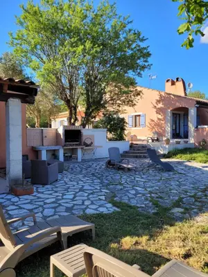a stone patio with chairs and a house at Location saisonnière villa Lauris in Lauris