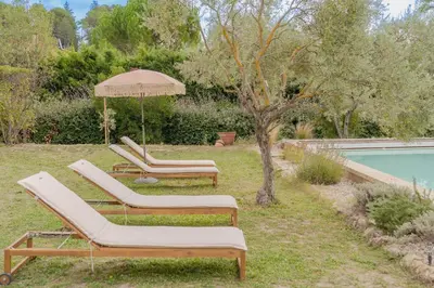 two lounge chairs and an umbrella next to a pool at Maison à 2 pas du Village D'ansouis à 30 Minutes D'aix-en-provence in Ansouis
