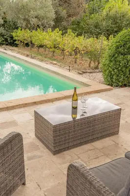 a bottle of wine sitting on a table next to a pool at Maison à 2 pas du Village D'ansouis à 30 Minutes D'aix-en-provence in Ansouis