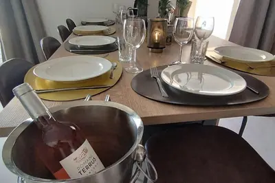 a table with plates and glasses and a bottle of wine at Gîte Aux Bons Voisins in Gordes