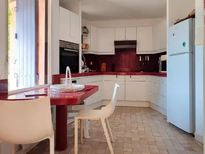 a kitchen with white cabinets and a red table and chairs at Holiday Home La Tourelle des Ocres by Interhome in Roussillon