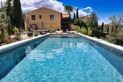 a large blue swimming pool in front of a house at Villa lavandin in Apt