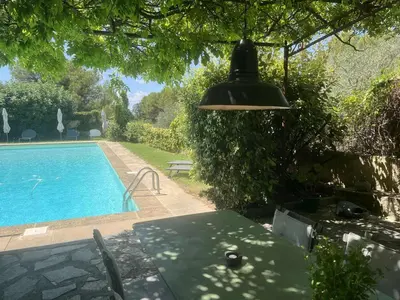 a light hanging over a table next to a swimming pool at Agréable maison de 65 m2 avec grande piscine in Aix-en-Provence
