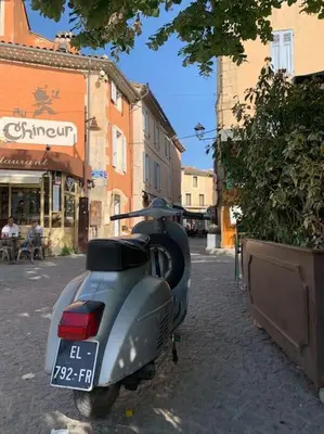 a motor scooter parked on the side of a street at La terrasse du pont jullian charme et calme dans le cœur historique in LʼIsle-sur-la-Sorgue