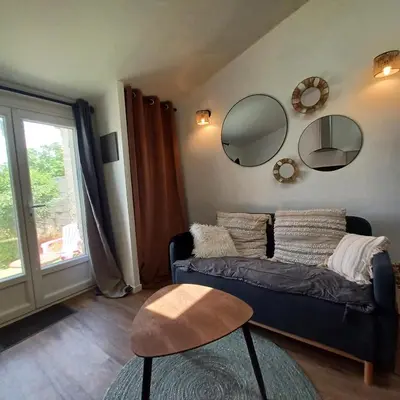 a living room with a couch and mirrors on the wall at Petit cocon avec terrasse in LʼIsle-sur-la-Sorgue