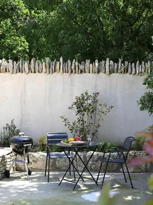 a patio with a table and chairs and a grill at Les Agapanthes de Gordes in Gordes