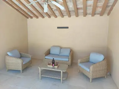 a patio with wicker chairs and a table with a bottle of wine at Mas La Gentille ,,, à la campagne , beautiful outdoor , swimming pool , pool house , Nice green Garden , BBQ ,,, only for you , pour passer un séjour inoubliable in Pernes-les-Fontaines