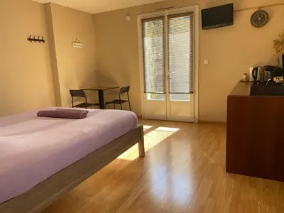 a bedroom with a bed and a table and a door at Casa Mia, chambre privée en Provence in LʼIsle-sur-la-Sorgue