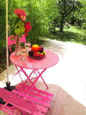 a pink table with a bowl of fruit and wine glasses at L'Islo Bamboo in Saumane-de-Vaucluse