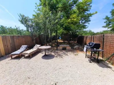 a backyard with a barbecue and a bench and a grill at adorable guest house avec jardin et parking privatif in Aix-en-Provence