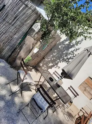 an outdoor patio with chairs and an umbrella at adorable guest house avec jardin et parking privatif in Aix-en-Provence