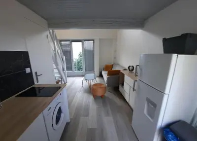 a small kitchen with a white refrigerator and a table at adorable guest house avec jardin et parking privatif in Aix-en-Provence