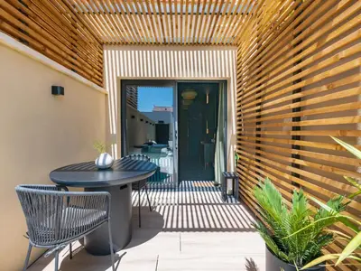 a patio with a table and chairs and a wooden wall at LOVE IN L'ISLE/SORGUE Le crépuscule in LʼIsle-sur-la-Sorgue