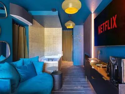 a living room with a blue couch and a bathroom at LOVE IN L'ISLE/SORGUE Le crépuscule in LʼIsle-sur-la-Sorgue