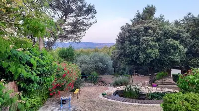 a garden with a table and some flowers and trees at Villa charmante à Mérindol avec piscine privée in Mérindol