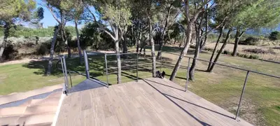 an open gate on a wooden deck with trees at Les pins du Luberon in Coustellet