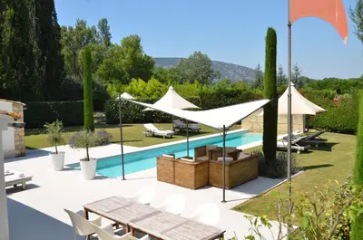 a garden with a swimming pool and white umbrellas at maison bertuli Oliviers Aircon, heated saltwater Pool, 2 Bedrooms in Oppède